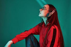 soñando mientras escucha la música. foto de estudio en interiores con luz de neón. retrato de una hermosa joven