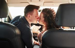 Moment of kiss. Beautiful people is in the modern car at their weekends photo