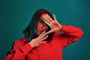 Gesturing with hands. Studio shot indoors with neon light. Portrait of beautiful young girl photo