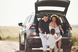 Give me hugs. Family have some good time at countryside near silver automobile at sunset photo