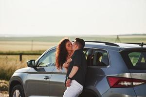 Happy couple kissing through the car window. Rural scene. At sunny day photo