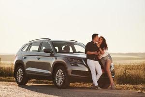 solo yo y tu. Encantadora pareja cerca de su nuevo coche moderno en tiempo de fin de semana foto