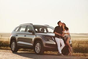 Look up. Lovely couple near their new modern car at weekend time photo