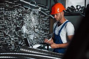 Wrtining in notepad. Man in uniform works on the production. Industrial modern technology photo