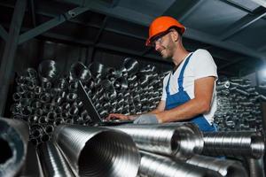 Nice results. Smiling guy. Man in uniform works on the production. Industrial modern technology photo