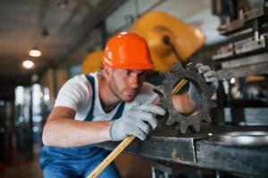 Yellow colored measuring tape. Man in uniform works on the production. Industrial modern technology photo