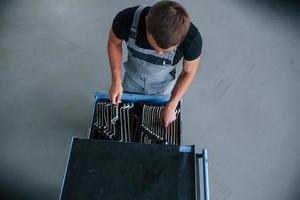 Wrenches of many sizes. Male mechanic use different tools to repair broken automobile in garage photo