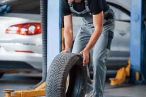 Order in execution. Mechanic holds a tire at the repair garage. Replacement of winter and summer tires photo