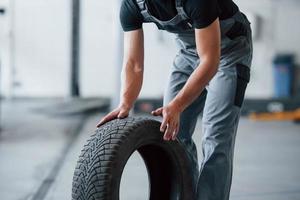 Photo in motion. Mechanic holds a tire at the repair garage. Replacement of winter and summer tires