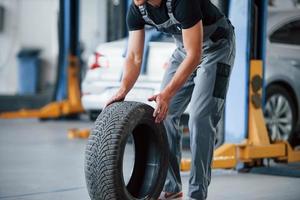 It's easier to walk that way. Mechanic holds a tire at the repair garage. Replacement of winter and summer tires photo