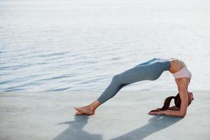 actividades de ocio. mujer joven con cuerpo delgado hace ejercicios contra el lago foto