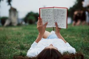 View from behind. Girl lying down on the green grass and have a rest photo