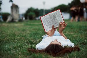 leyendo algunas notas. niña acostada en la hierba verde y descansar foto