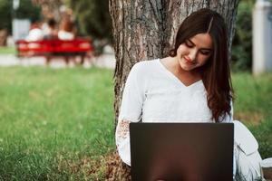 Using internet. Young woman have weekend and sits in the park at daytime photo