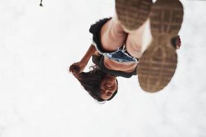 Looks down and smiles. Woman in casual clothes stands on glass at daytime photo