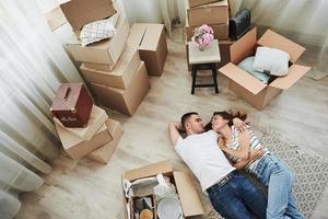 Taking a rest. Lying down on the floor. Cheerful young couple in their new apartment. Conception of moving photo