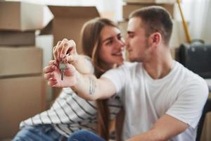 Holds keys of their new house. Successful people. Cheerful young couple in their new apartment. Conception of moving photo