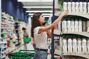 Using smartphone. Female shopper in casual clothes in market looking for products photo