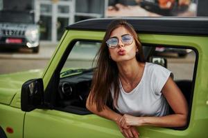 Pretty woman in the green modern car posing for the camera photo