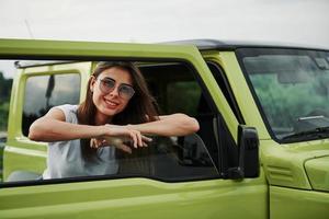 Pretty Woman en el coche moderno verde posando para la cámara foto