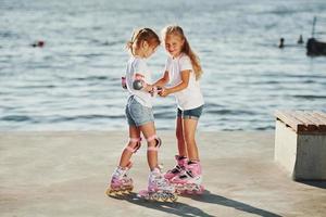 dos niños aprendiendo a andar en patines durante el día cerca del lago foto