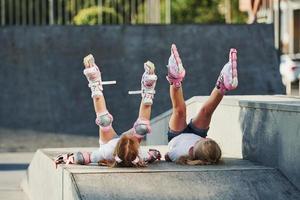 Legs up. Feeling free. On the ramp for extreme sports. Two little girls with roller skates outdoors have fun photo