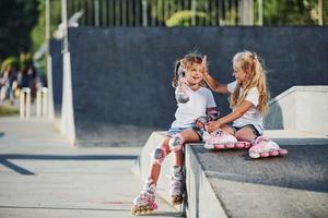 On the ramp for extreme sports. Two little girls with roller skates outdoors have fun photo