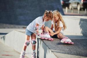 clima cálido. en la rampa para los deportes extremos. dos niñas pequeñas con patines al aire libre se divierten foto
