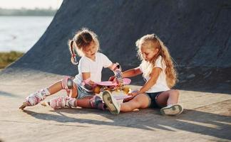 probando patines nuevos. dos lindas niñas se divierten al aire libre en el parque foto