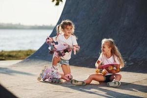 probando patines nuevos. dos lindas niñas se divierten al aire libre en el parque foto