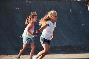 Having fun with bubbles. Leisure activities. Two little girls having fun in the park photo