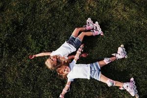 Top view. Feeling freedom. Two female kids lying on the green grass at summertime photo