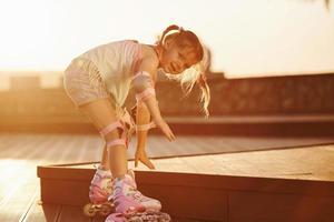 niño lindo feliz montando en sus patines. increíble luz del sol foto