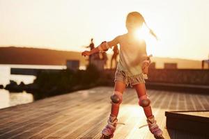 Happy cute kid riding on her roller skates. Unbelievable sunlight photo