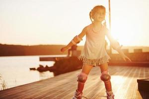 Happy cute kid riding on her roller skates. Unbelievable sunlight photo