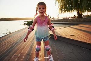 Happy cute kid riding on her roller skates. Summertime leisure and weekends photo