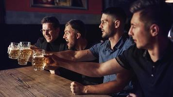 tres aficionados al deporte en un bar viendo fútbol. con cerveza en las manos foto