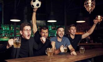 con balón de fútbol. es una meta celebrando la victoria. tres fanáticos de los deportes en un bar viendo fútbol con cerveza en las manos