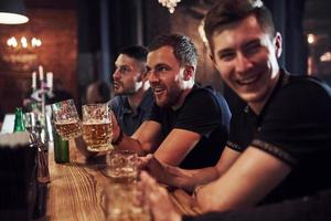 gente positiva amigos descansando en el pub con cerveza en las manos. teniendo una conversación foto