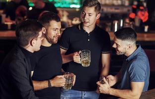 ambiente cálido amigos descansando en el pub con cerveza en las manos. teniendo una conversación foto