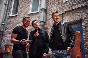 Three male friends stands outside the bar. Having conversation. In nice clothes photo