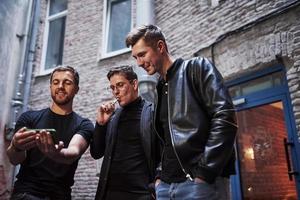 Three male friends stands outside the bar. Having conversation. In nice clothes photo