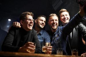 Tomando una foto. amigos descansando en el pub con alcohol en las manos. teniendo una conversación foto