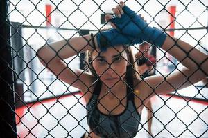 Taking a break. Sportswoman at boxing ring have exercise. Leaning on the fence photo