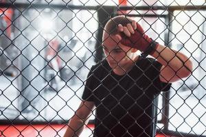 Taking a break. Sportsman at boxing ring have exercise. Leaning on the fence photo