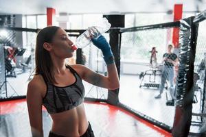 Drinks water. Taking a break. Sportswoman at boxing ring have exercise photo