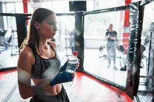 Drinks water. Taking a break. Sportswoman at boxing ring have exercise photo