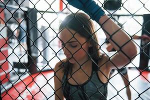 Taking a break. Sportswoman at boxing ring have exercise. Leaning on the fence photo