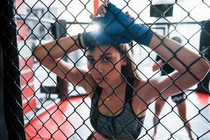 Taking a break. Sportswoman at boxing ring have exercise. Leaning on the fence photo