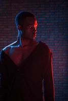 Vertical photo. Futuristic neon lighting. Young african american man in the studio photo